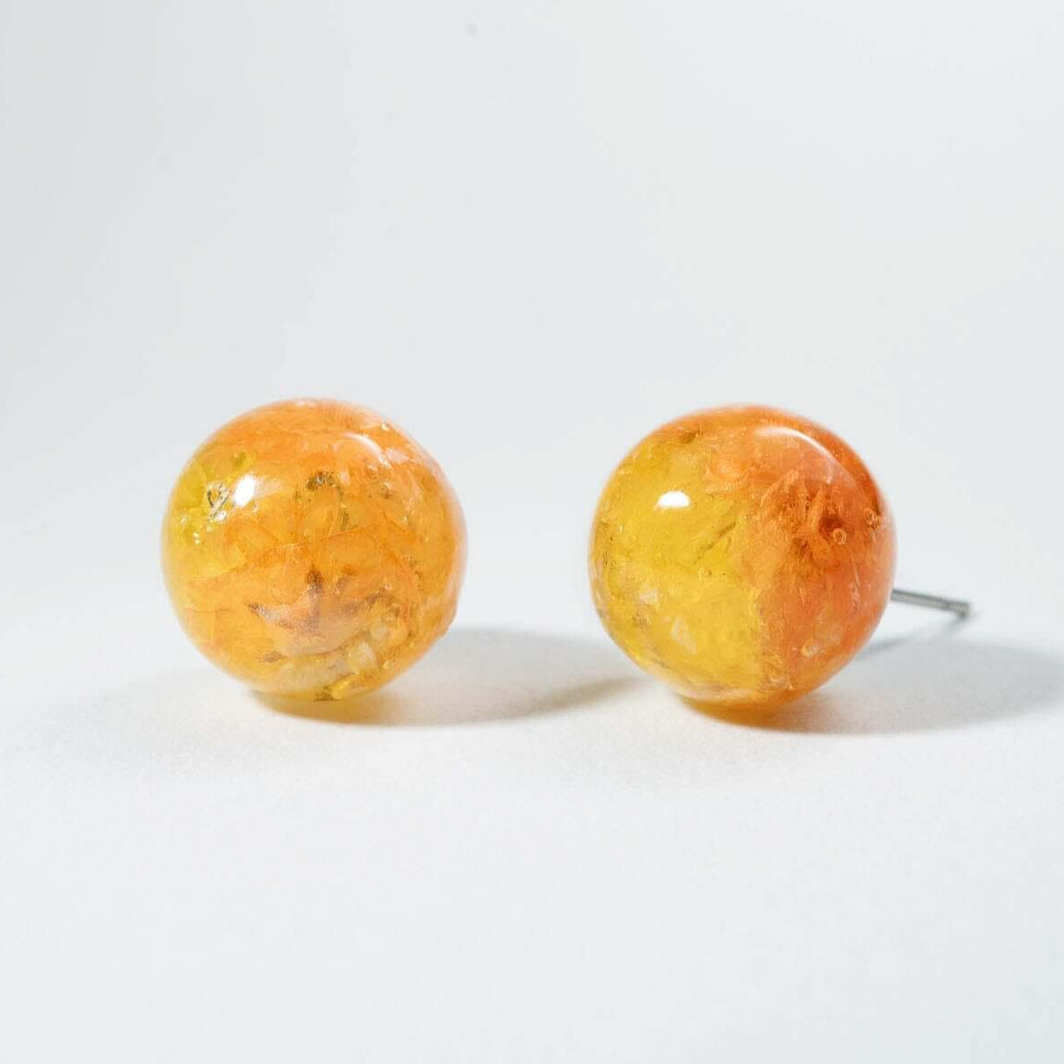 Pair of orange spherical earrings on a light gray background